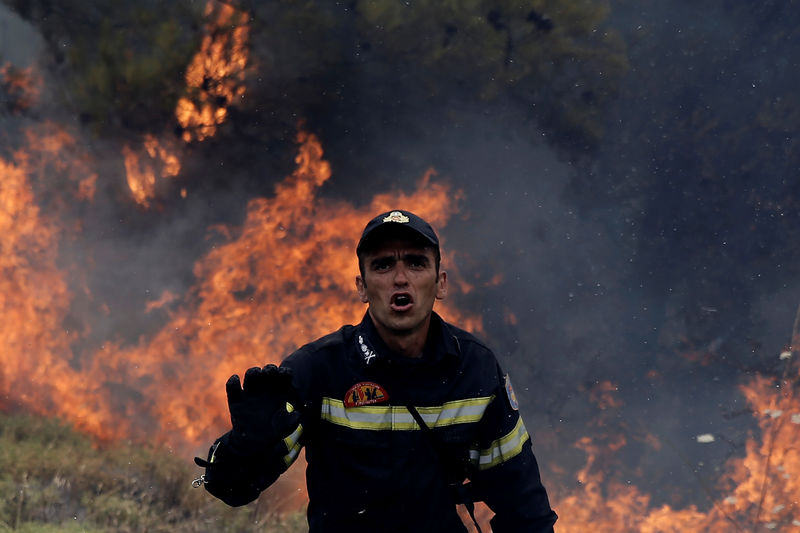© Reuters. رجال الإطفاء يكافحون حرائق الغابات قرب أثينا لليوم الثالث