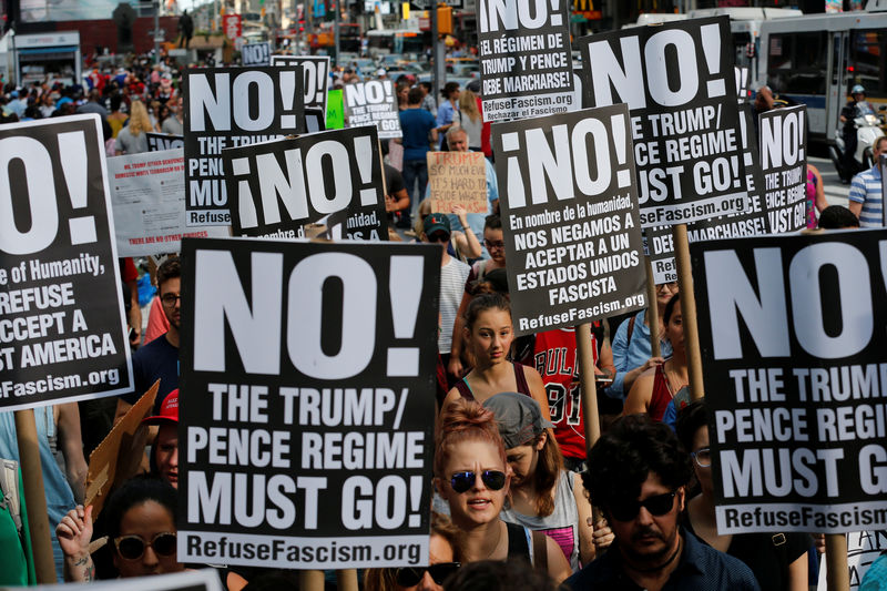 © Reuters. Protesters hold signs reading "No! The Trump/Pence regime must go!" during a march against white nationalism in New York City