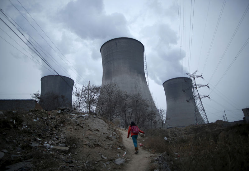 © Reuters. FILE PHOTO - A girl makes her way to her house located next to the cooling towers of a coal-fired power plant in Shijiazhuang