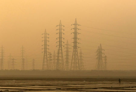© Reuters. FILE PHOTO: A worker levels a salt pan near electricity pylons in Mumbai