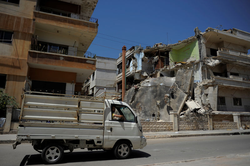 © Reuters. A truck passes a damaged building in Waer district in the central Syrian city of Homs