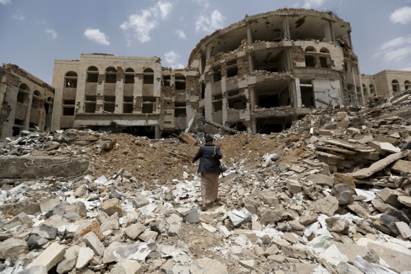 © Reuters. Houthi militant walks in front of a government compound, destroyed by recent Saudi-led air strikes, in Yemen's northwestern city of Amran