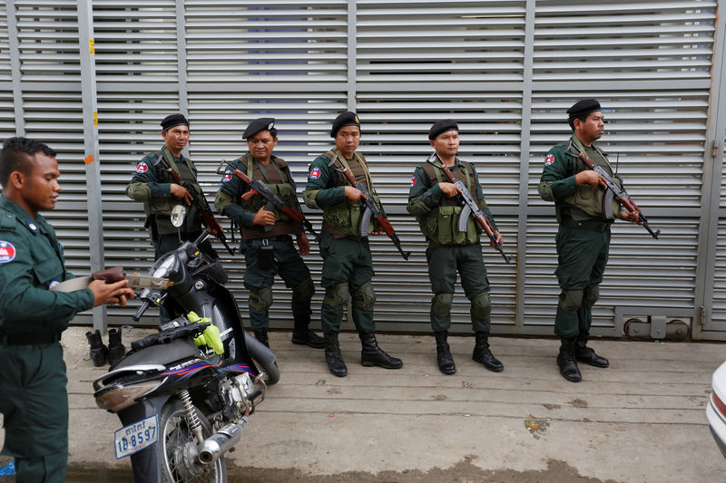 © Reuters. Cambodia police stand at a condo where they arrested dozens of young Chinese men and women working on a call centre to carry out a telephone and internet scam on victims in China in Phnom Penh