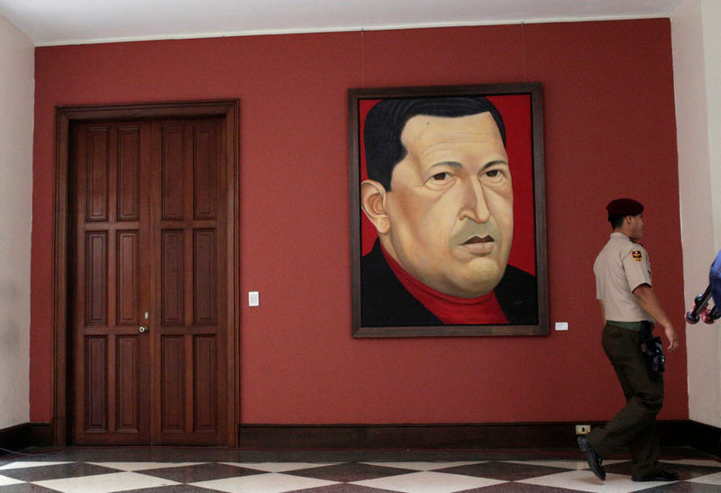 © Reuters. A member of the National Guard walks in front of a painting of late Venezuela's President Hugo Chavez in Caracas