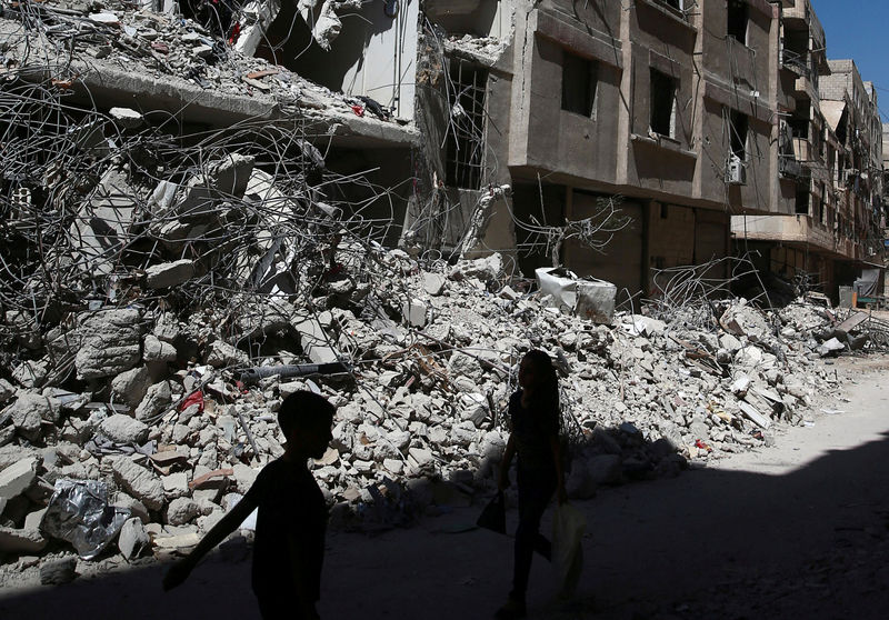 © Reuters. Niños caminan junto a edificios destruidos en Ain Tarma, en el suburbio de Ghouta, en el este de Damasco