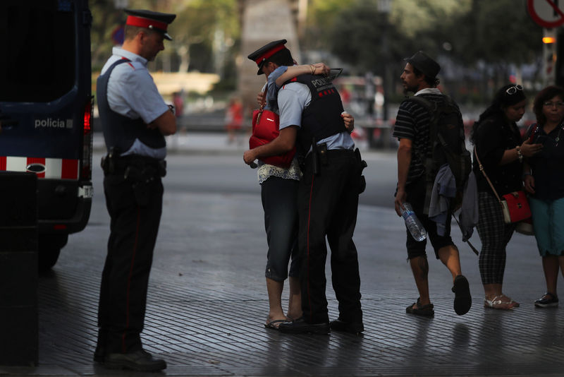 © Reuters. Pilar Revilla, 75, hugs a Catalan Mossos d'Esquadra officer after visiting an impromptu memorial where a van crashed into pedestrians at Las Ramblas in Barcelona