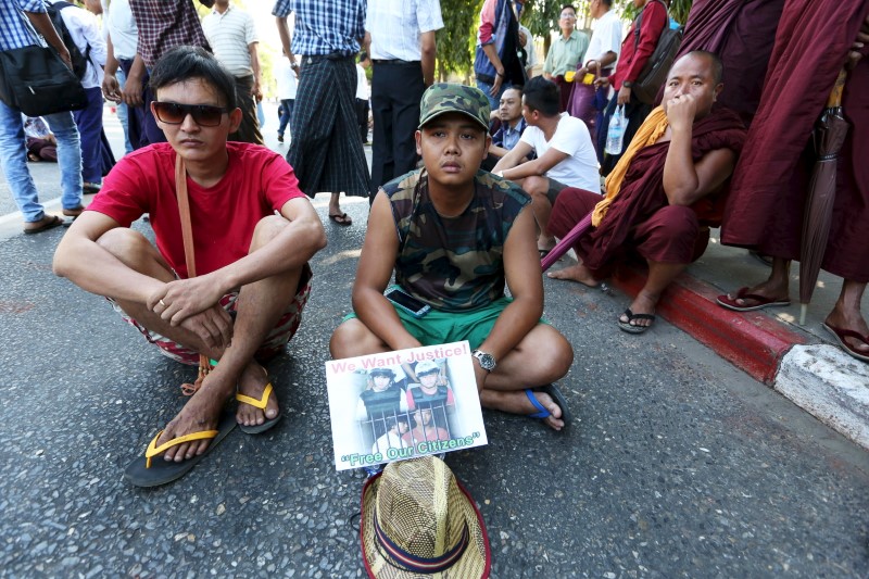 © Reuters. Protesters sit on the road as they protest in support of Myanmar migrant workers Zaw Lin and Win Zaw Htun in front of the Thai embassy in Yangon