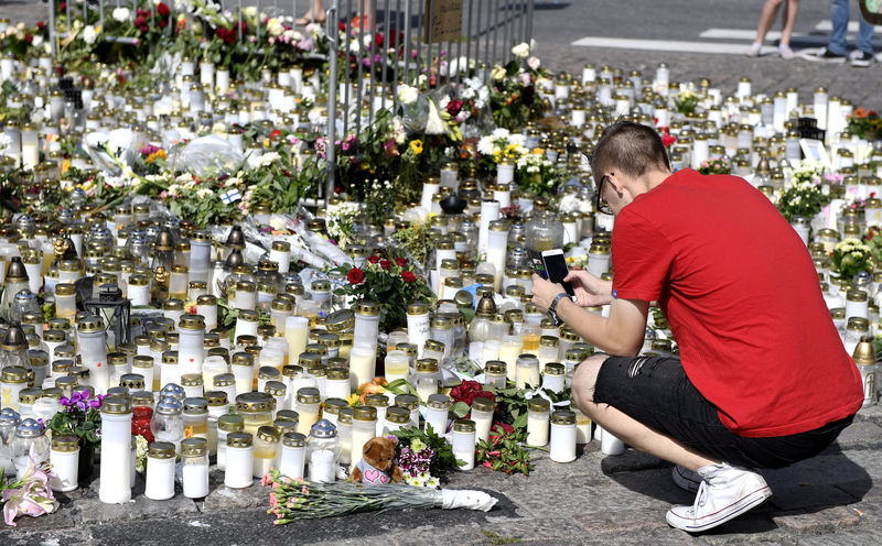 © Reuters. Mourners bring memorial cards, candles and flowers to the Turku Market Square, in Turku