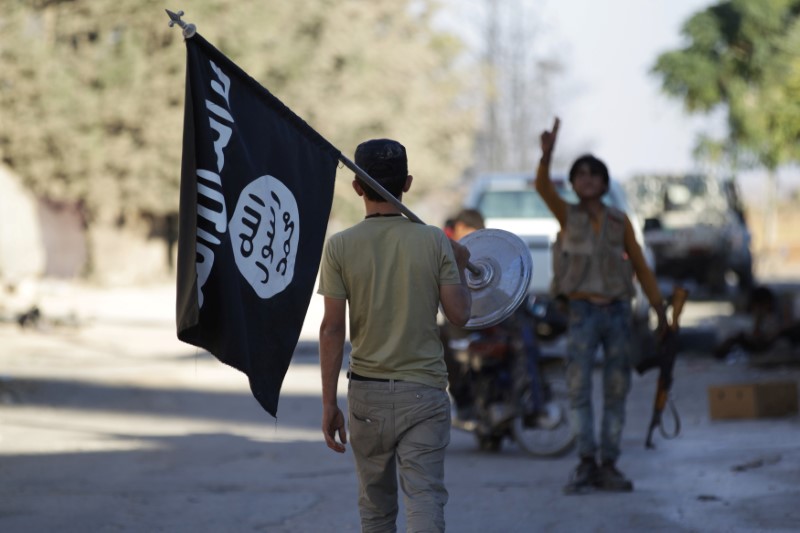 © Reuters. FILE PHOTO: A rebel fighter takes away a flag that belonged to Islamic State militants in Akhtarin village, after rebel fighters advanced in the area, in northern Aleppo Governorate
