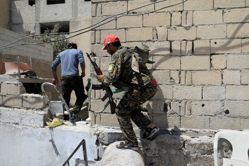 © Reuters. Member of the Syrian Democratic Forces moves from house to house to hide from Islamic State's sniper in the old city of Raqqa