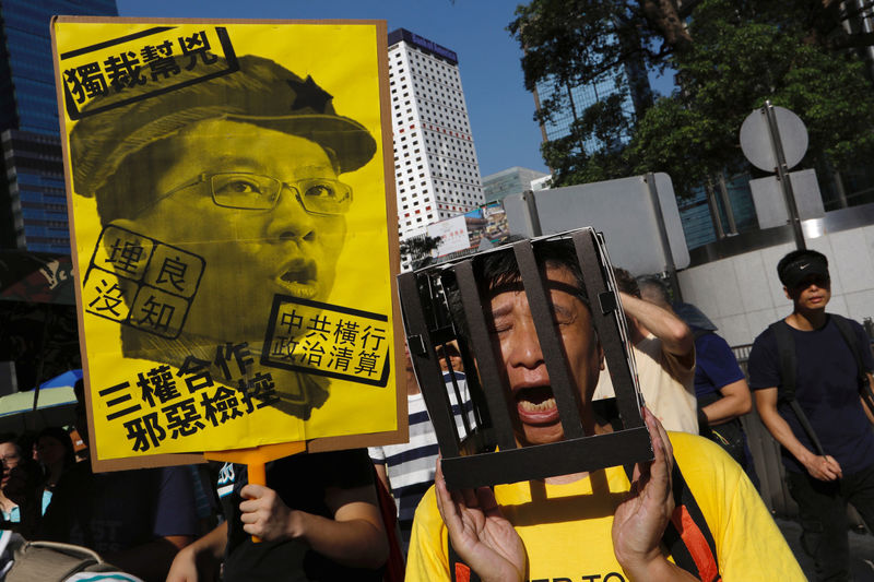 © Reuters. Demonstrator holds cardboard jail bars as he protests student leaders' jailing in Hong Kong