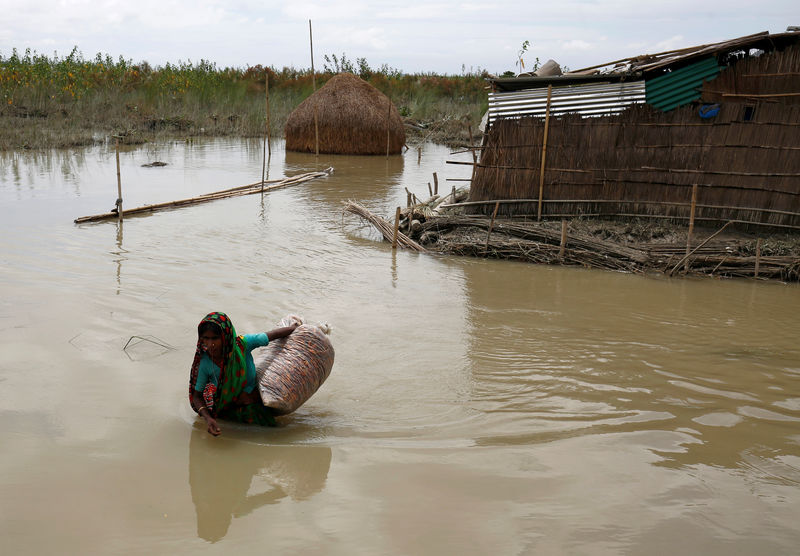 © Reuters. Mulher carrega pertences em área alagada em Gaibandha, Bangladesh