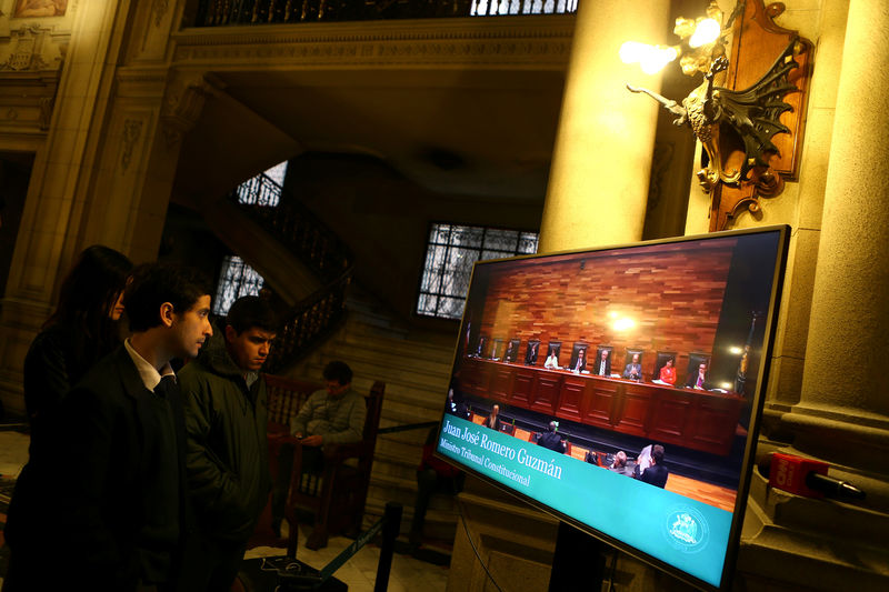 © Reuters. Media members look on a screen as members of the Constitutional Tribunal discuss the legality of a bill that would allow for abortions in certain cases, in Santiago