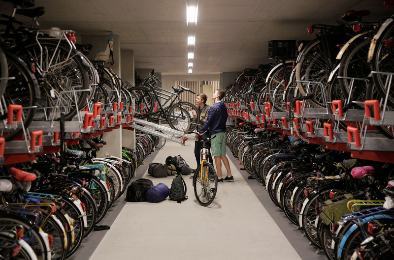 © Reuters. Dos ciclistas dejan sus bicicletas en el mayor estacionamiento para bicicletas del mundo en Utrecht