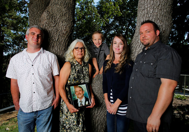 © Reuters. Nancy Schrock holds a picture of her late husband Thomas as she poses for a photograph between her family