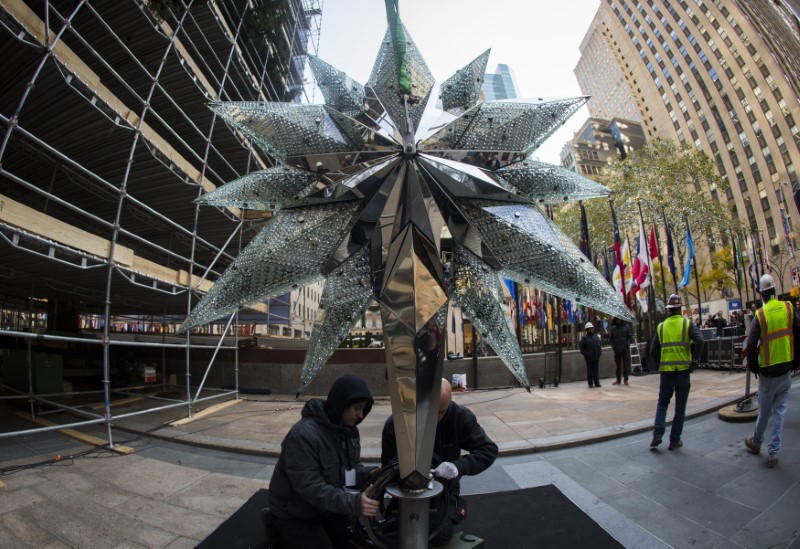 © Reuters. Workers make adjustments to the Swarovski Star before raising it to the top of the Rockefeller Center Christmas Tree which is being decorated behind scaffolding at Rockefeller Center in New York City