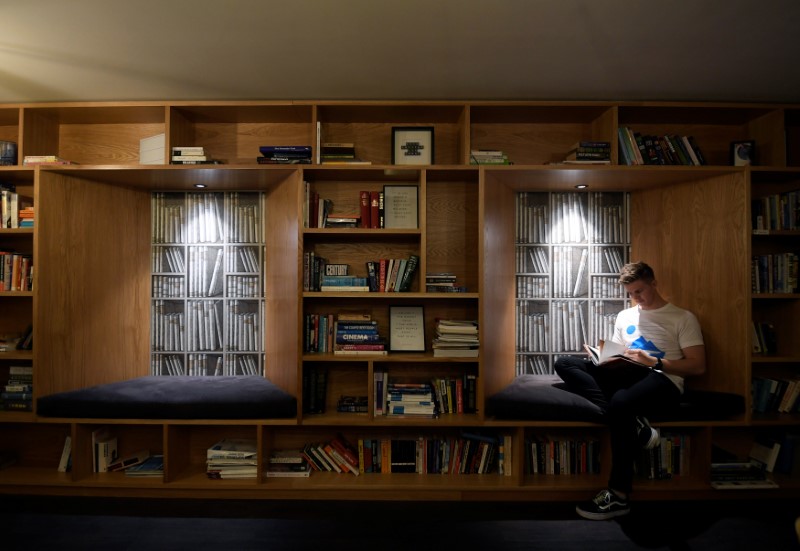 © Reuters. A resident or 'member' relaxes in a library communal space with books all donated by other tenants to share  at The Collective co-living building in west London