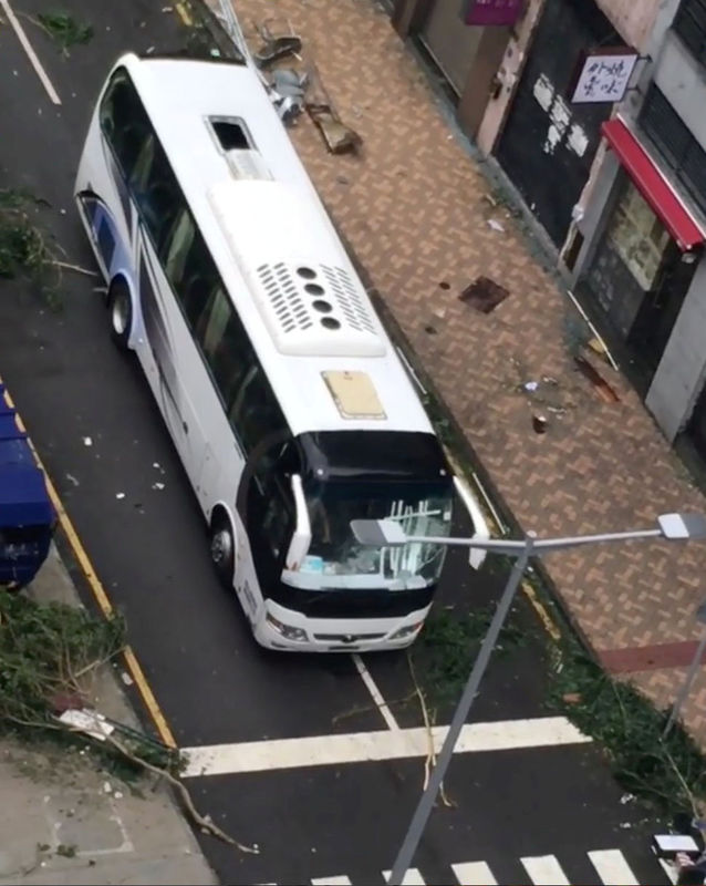 © Reuters. A bus drives past tree branches and debris along a street in Macau during Typhoon Hato