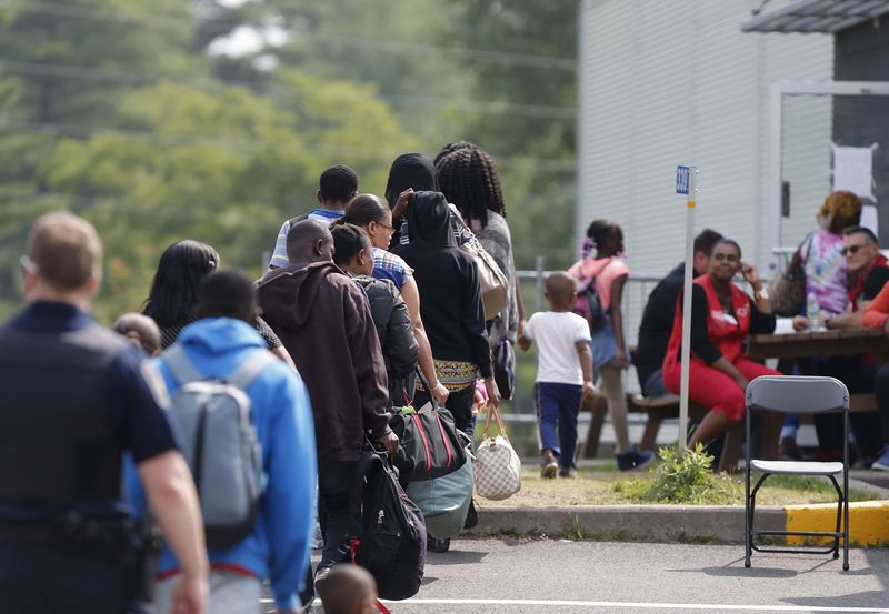 © Reuters. A group of asylum seekers wait to be processed after being escorted from their tent encampment to the Canada Border Services in Lacolle