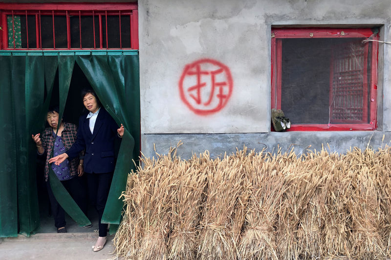 © Reuters. Women walk out of a village house slated for demolition in Shahezi