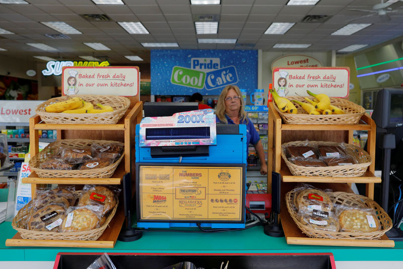 © Reuters. An employee stands behind a lottery machine at the Pride convenience store where a winning more than $750 million Powerball ticket was sold in Chicopee