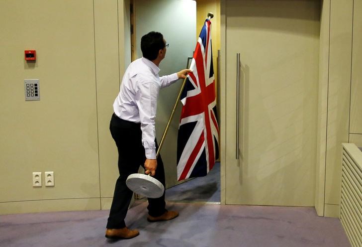 © Reuters. FILE PHOTO: An official carries a Union Jack flag ahead of a news conference by Britain's Secretary of State for Exiting the European Union Davis and EU's chief Brexit negotiator Barnier in Brussels