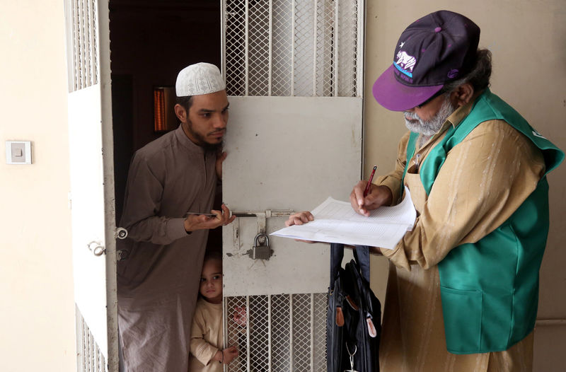 © Reuters. FILE PHOTO: A census enumerator notes details from a resident during Pakistan’s 6th population census in Karachi