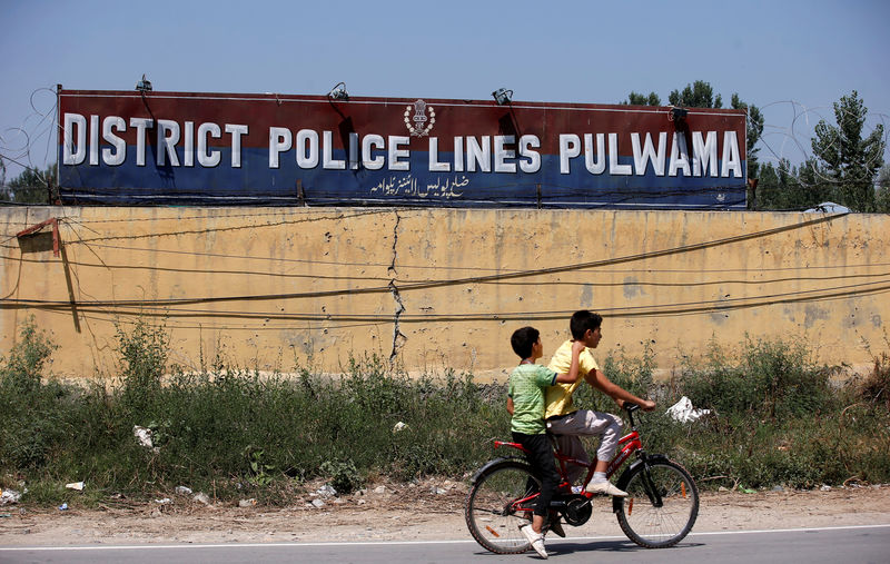 © Reuters. Boys paddle their cycle past a police camp after it was attacked by suspected militants on Saturday in south Kashimir's Pulwama district