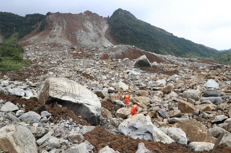 © Reuters. Rescue workers search for survivors at the site of a landslide that occurred in Nayong county