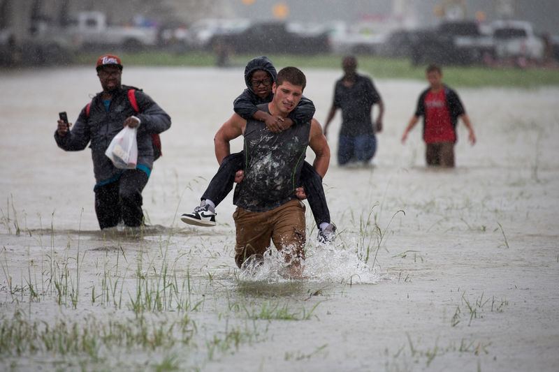 © Reuters. Homem ajuda menino durante tempestade Harvey em Houston