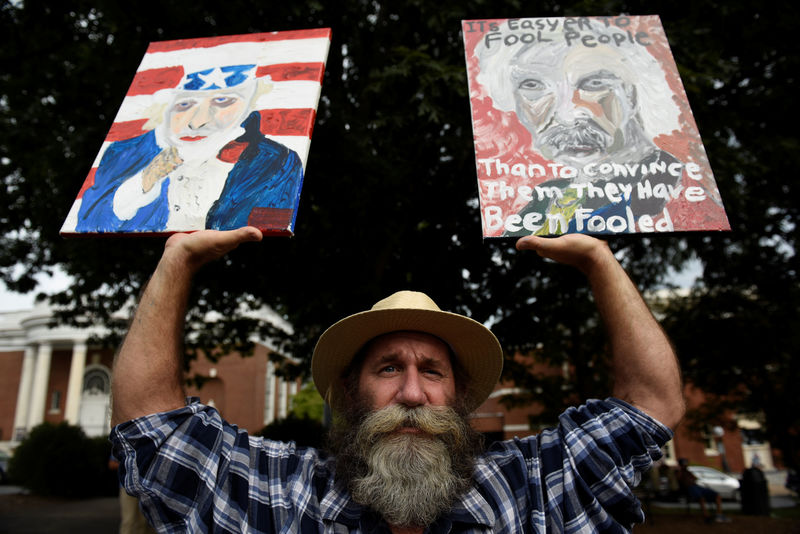 © Reuters. Daniel Gray, an artist from Crozet, Virginia, holds his paintings before "Charlottesville to D.C: The March to Confront White Supremacy," a ten-day trek