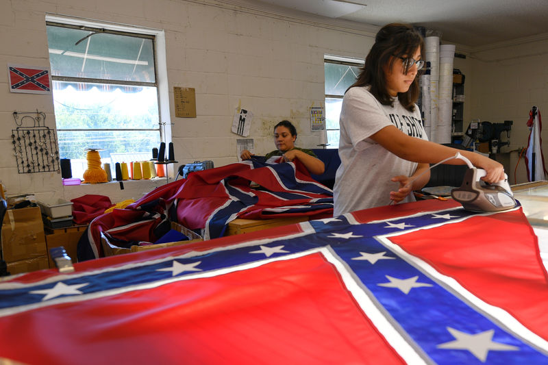 © Reuters. Cynthia Hernandez places stars on a Confederate Battle Flag in the Alabama Flag & Banner shop in Huntsville