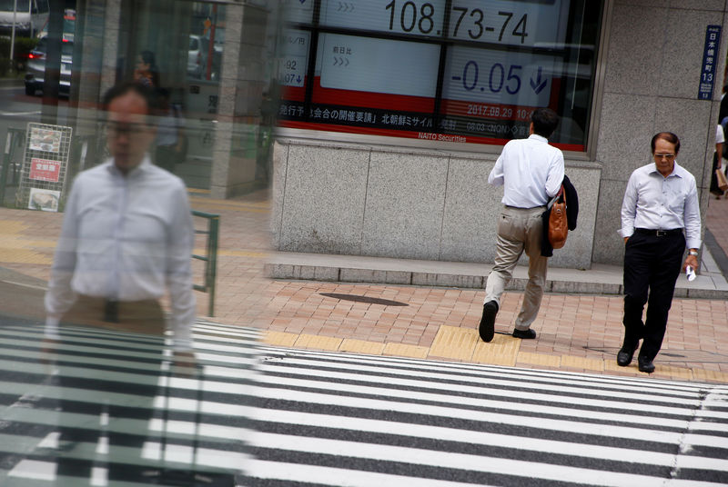 © Reuters. Pedestrians walk past an electronic board showing the exchange rate between the yen and the U.S. dollar outside a brokerage at a business district in Tokyo