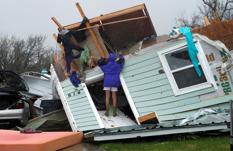 © Reuters. FILE PHOTO:    A woman uses a coat hanger to try and retrieve an item from a destroyed house after Hurricane Harvey struck Fulton