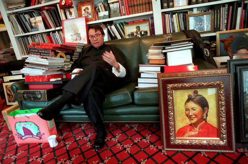 © Reuters. FILE PHOTO: Flamboyant businessman David Tang, holding his trademark Cuban cigar, speaks during an interview in his office in Hong Kong