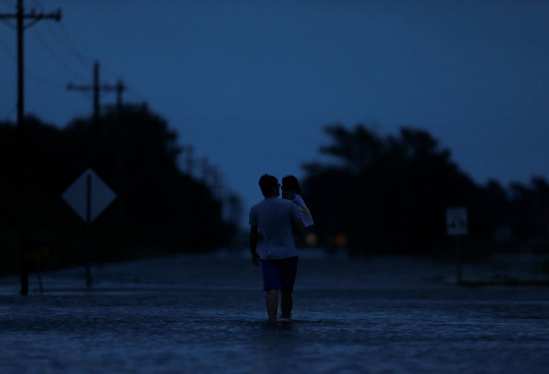 © Reuters. Ethan carrega sua filha de 2 anos, Zella, enquanto anda por área alagada pela tempestade tropical Harvey, em Iowa, Louisiana