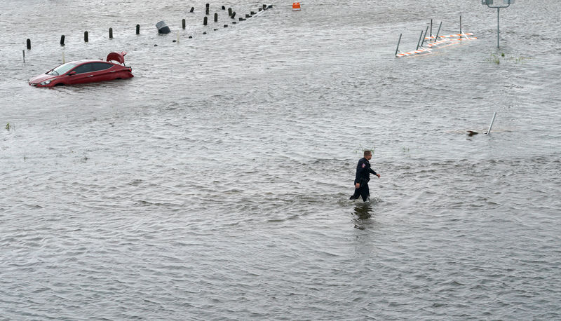 © Reuters. A police officer wades through the Hurricane Harvey floodwaters in Alvin