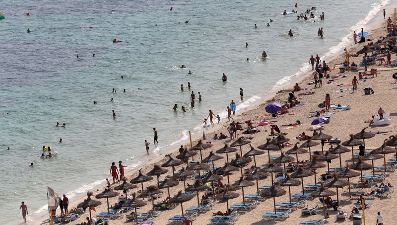 © Reuters. FILE PHOTO - Tourists sunbathe and swim at the beach of Magaluf on the island of Mallorca