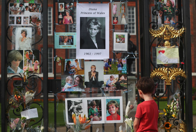 © Reuters. Menino observa homenagem deixada para princesa Diana nos portões do palácio de Kensington, em Londres