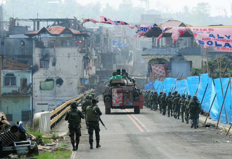 © Reuters. An Armoured Personnel Carrier (APC) and government troops march towards Mapandi bridge after 100 days of intense fighting between soldiers and insurgents from the Maute group, who have taken over parts of Marawi city