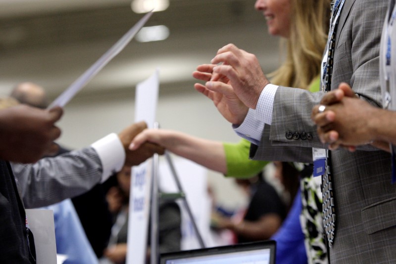 © Reuters. FILE PHOTO: Corporate recruiters gesture and shake hands as they talk with job seekers in Washington