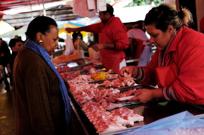 © Reuters. Comerciante vende carne de frango a consumidora em feira de São Paulo, Brasil