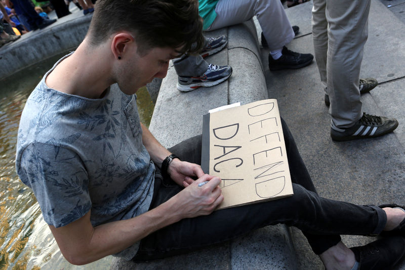 © Reuters. FILE PHOTO: A protester writes a sign that reads "Defend DACA" at a protest against U.S. President Donald Trump's proposed end of the DACA program that protects immigrant children from deportation in New York City