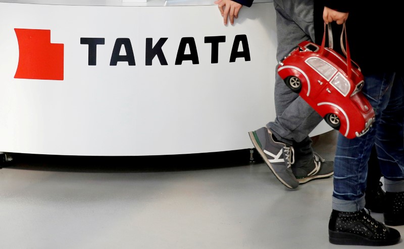 © Reuters. FILE PHOTO - Visitors walk past a logo of Takata Corp on its display at a showroom for vehicles in Tokyo