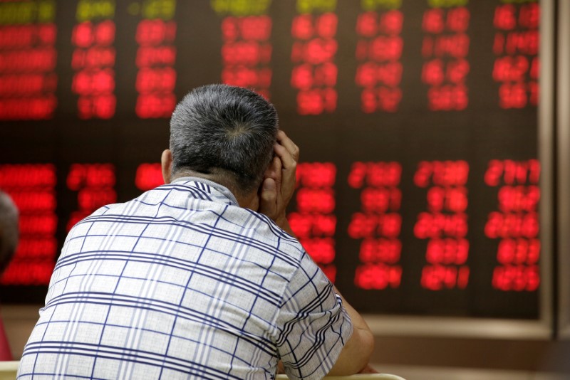 © Reuters. An investor looks at an electronic board showing stock information in Beijing