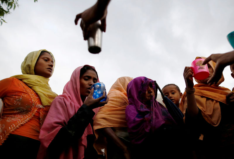 © Reuters. Local Bangladeshi people offer water as Rohingya refugees arrive in Teknaf