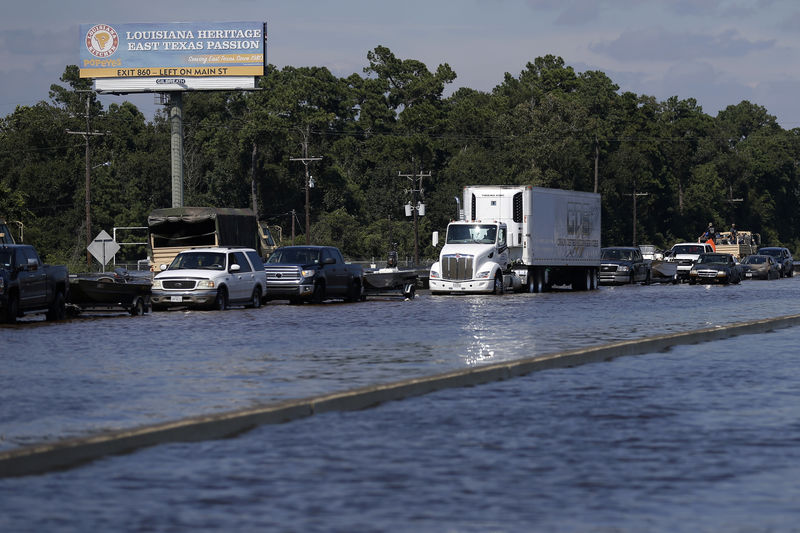 © Reuters. Autos conducen a través del agua de la inundación de la tormenta tropical Harvey en la ciudad de Rose, Texas