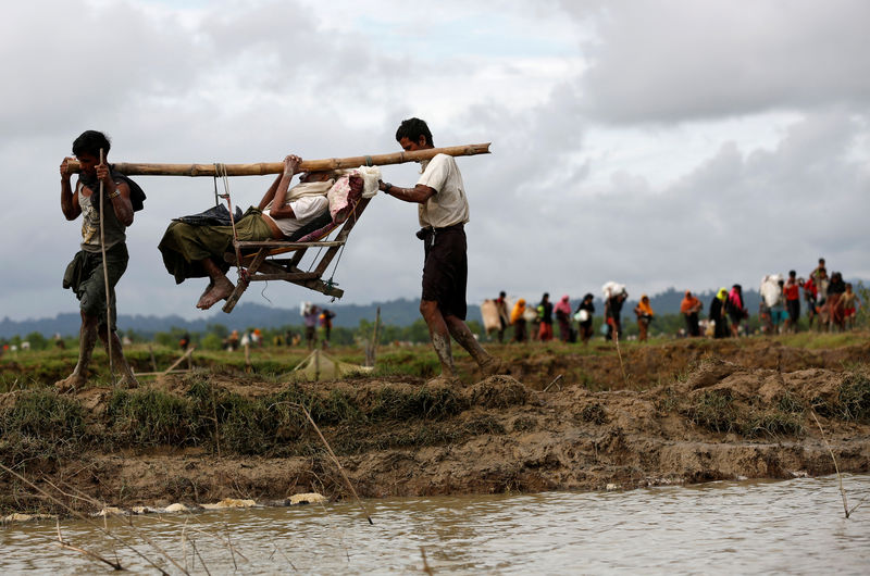 © Reuters. Rohingya refugee men carry a man after travelling over the Bangladesh-Myanmar border in Teknaf