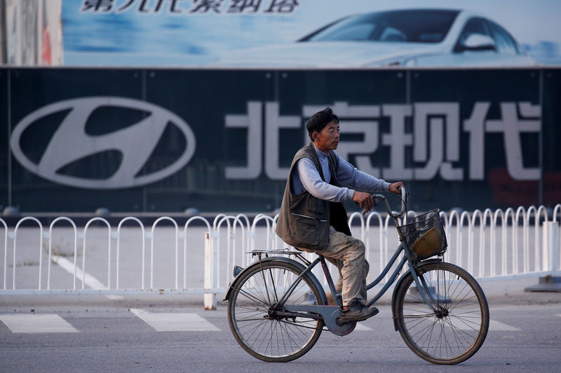 © Reuters. FILE PHOTO: A man cylces past a gate of Hyundai Motor Co plant in Beijing