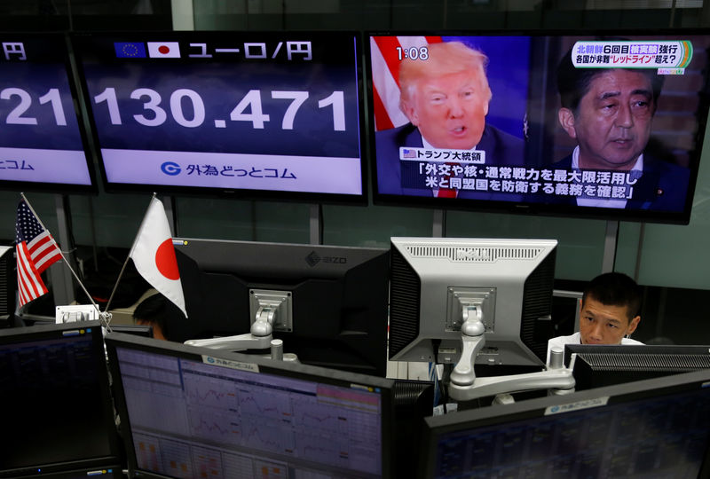 © Reuters. An employee of a foreign exchange trading company works near a monitor showing Japan's Prime Minister Shinzo Abe and U.S. President Donald Trump in a television news report about their telephone conference on North Korea's threat in Tokyo